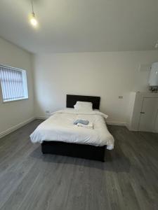 een slaapkamer met een bed met witte lakens en houten vloeren bij Vic Vic property in Oldham