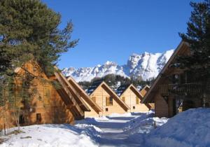a group of buildings in the snow with mountains in the background at CHALET DES PAZ in Le Dévoluy