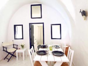 un comedor blanco con una mesa y sillas blancas en Blu Bianco Cave House by SV, en Oia