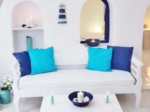 Sofá blanco con almohadas azules y velas en Blu Bianco Cave House by SV, en Oia