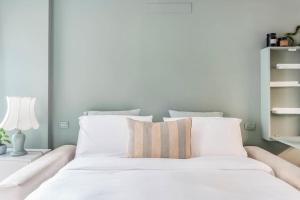 Una cama con sábanas blancas y una almohada. en Bergamo Center [SUITE MIA] - Modern & Green + WiFi, en Bérgamo