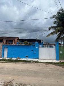 un edificio azul con una valla blanca y una palmera en Casa de Praia Coroa Vermelha, en Santa Cruz Cabrália