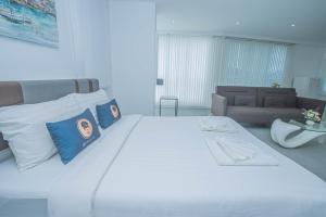 un grande letto bianco con cuscini blu in una stanza di Utopia Kata By RoomQuest a Phuket