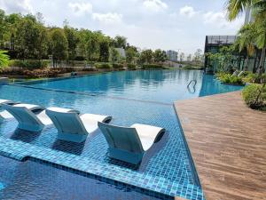 una piscina con sillas azules y blancas en un complejo en Greenfield Residence @ Sunway 3R2B 3-7 Pax Free 2 Parking Condo, en Petaling Jaya