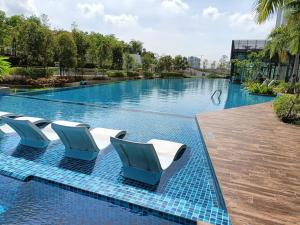 una piscina con sedie blu e bianche in un resort di Greenfield Residence at Sunway 3R2B by Convivial Staycation B03 a Petaling Jaya