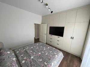 a bedroom with a bed and a flat screen tv at MA apartments in Mažeikiai