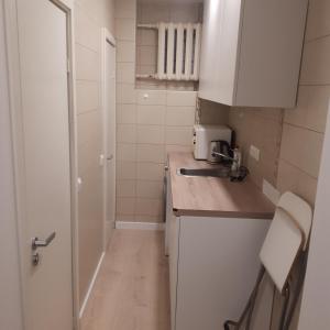 uma pequena cozinha com armários brancos e um lavatório em Mini apart Žvėrynas em Vilnius