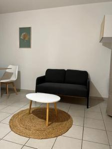 uma sala de estar com um sofá preto e uma mesa em Charmant Studio proche remparts et commerces em Avignon
