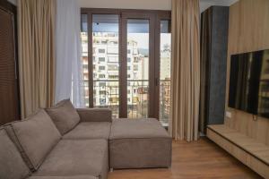 a living room with a couch and a large window at Signature apartment 8 in Tirana