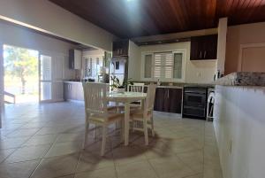 una cucina con tavolo e sedie in una stanza di Ampla casa de sítio com lagoa. a Jaguaruna