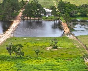 an aerial view of a pond in a field at Ampla casa de sítio com lagoa. in Jaguaruna