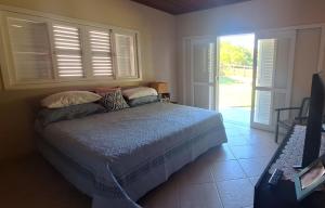 a bedroom with a bed and a window with shutters at Ampla casa de sítio com lagoa. in Jaguaruna