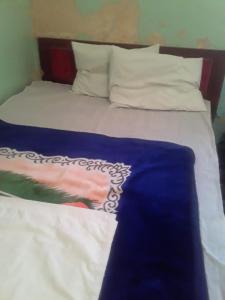 a bed with blue and white sheets and pillows at hotel atlas in Imilchil