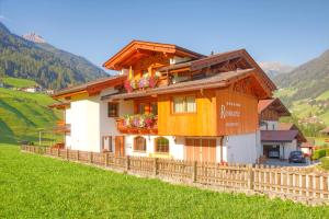 ein Haus auf einem Hügel mit einem Zaun in der Unterkunft Haus Rosmarie in Neustift im Stubaital