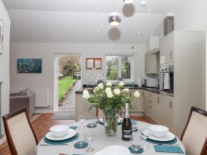 eine Küche und ein Esszimmer mit einem Tisch und einer Vase aus Blumen in der Unterkunft Hazelnut Lodge in Crediton