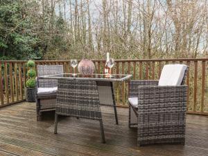 a patio with a table and chairs on a deck at Hazelnut Lodge in Crediton