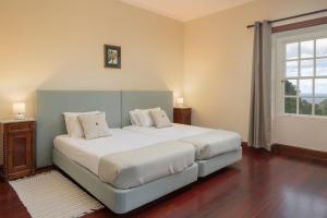 een slaapkamer met een bed met witte lakens en een raam bij Casa da Fajã Alta with breakfast by An Island Apart in Jogo da Bola