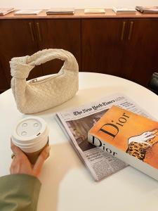 a woman holding a cup of coffee and a purse and a newspaper at The Evelyn NoMad in New York