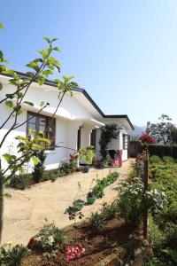 een klein wit huis met planten ervoor bij Dawn's Bungalow in Nuwara Eliya