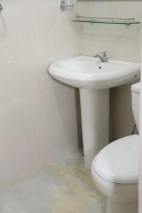 een witte badkamer met een wastafel en een toilet bij Dawn's Bungalow in Nuwara Eliya