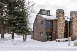 ein Holzhaus im Schnee mit einem Baum in der Unterkunft Wister A in Jackson