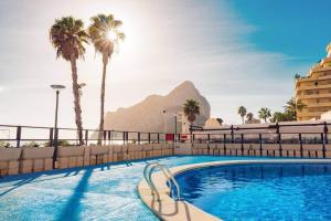a pool with palm trees and a mountain in the background at Apartamento Topacio 2 - PlusHolidays in Calpe