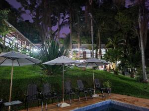 een groep stoelen en parasols naast een zwembad bij Pousada do Rodrigo in Macacos