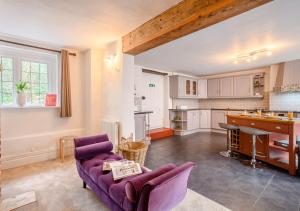 a living room with a purple couch and a kitchen at Grove Cottage in Horstead