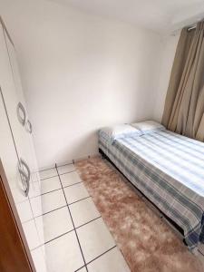 a small bedroom with a bed and a rug at Apartamento próximo da Praia in Vila Velha