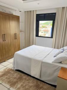 - une chambre avec un grand lit blanc et une fenêtre dans l'établissement Apartamento próximo da Praia, à Vila Velha