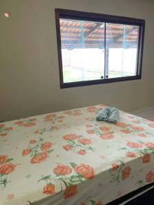ein Bett mit einer floralen Bettdecke darauf mit einem Fenster in der Unterkunft Refúgio Aconchegante e Espaçoso in Araguaína