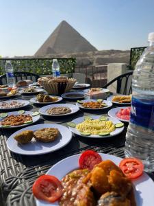 una mesa cubierta con platos de comida con una pirámide en Solima pyramids inn, en El Cairo