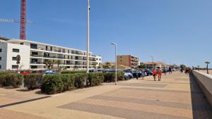 a person walking down a sidewalk next to a parking lot at Archipel Capri in Valras-Plage