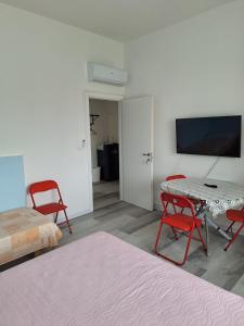 a room with a table and chairs and a tv at Giada Rooms in Peschiera del Garda