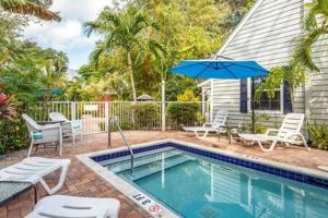 a swimming pool with chairs and an umbrella next to a house at Road's End by Brightwild in Key West