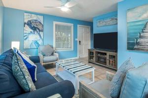 a blue living room with a couch and a tv at Road's End by Brightwild in Key West