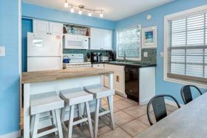 uma cozinha com paredes azuis e uma mesa e cadeiras em Road's End by Brightwild em Key West