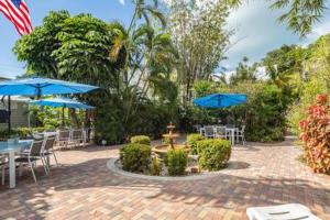 a patio with tables and chairs with blue umbrellas at Road's End by Brightwild in Key West