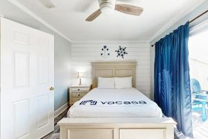 a bedroom with a white bed and blue curtains at Panhandle Luxury D in Panama City Beach