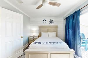 ein Schlafzimmer mit einem weißen Bett und blauen Vorhängen in der Unterkunft Panhandle Luxury D in Panama City Beach