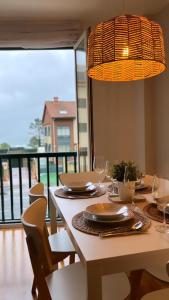 a dining table with chairs and a chandelier at Piso Av Galicia playa in Finisterre