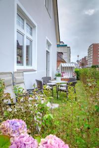 een patio met een tafel, stoelen en bloemen bij Steuerbord in Westerland