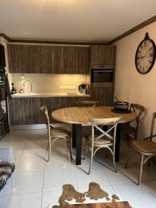 eine Küche mit einem Tisch, Stühlen und einer Uhr in der Unterkunft les 7 laux immobilier chalet E in Prapoutel