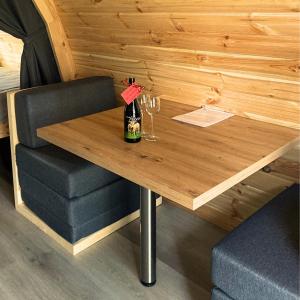 una mesa de madera con 2 copas y una botella de vino en Camping Sérendipité, en Neuvéglise