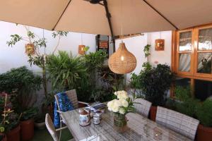 a wooden table with flowers and an umbrella at Bamba House Cusco in Cusco