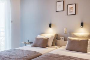Ciel Comfort Living في لاغاناس: سريرين في غرفة بجدران بيضاء