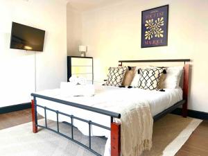 una camera da letto con un letto con lenzuola bianche e una TV di 2 Bed- Camden Town a Londra