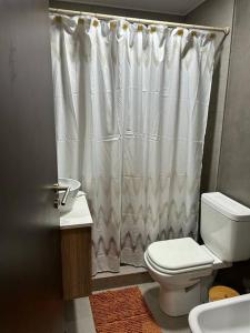 baño con aseo y cortina de ducha blanca en Comodidad y lujo! Con desayuno Incluido! G&A Rent en Ezeiza