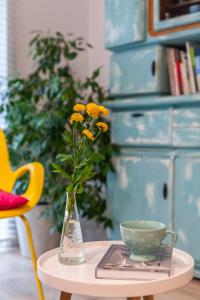 a vase with yellow flowers and a cup on a table at Apartament Bulwary Łyna przy Starym Mieście in Olsztyn