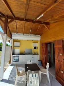 eine Terrasse mit einem Tisch und Stühlen sowie eine Küche in der Unterkunft bungalow Bô Sicrié in Le Moule